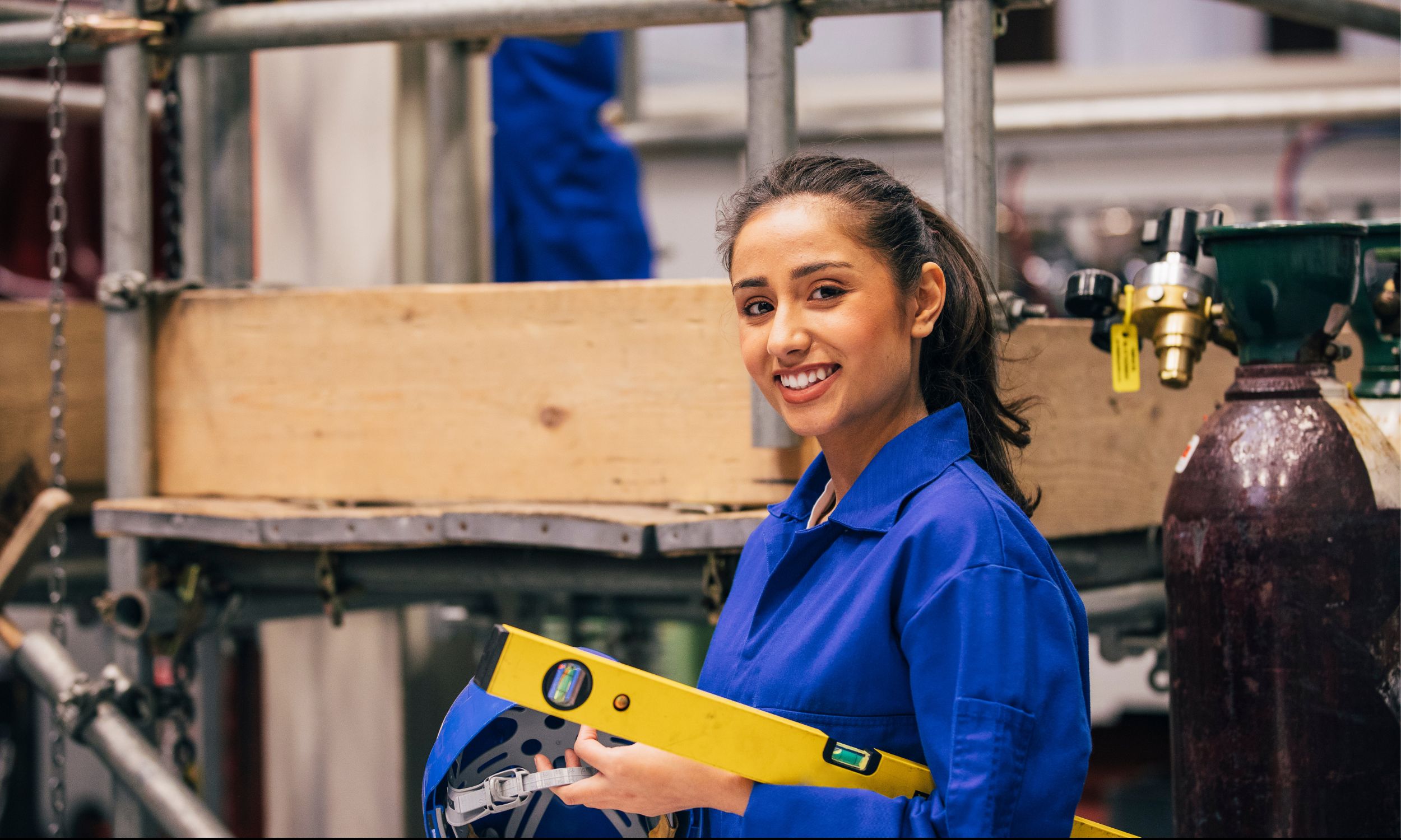 A female engineering student wearing a blue jumpsuit and holding a spirit level in a workshop setting at St. Mary's Group of Institutions