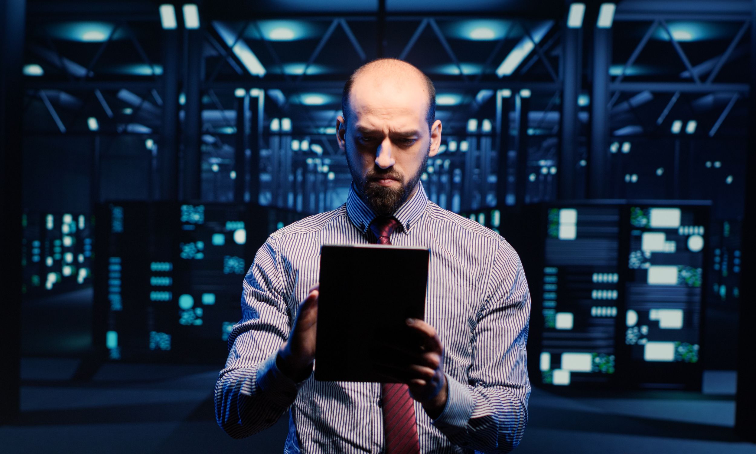 A professional in a futuristic server room holding a tablet, surrounded by illuminated screens, symbolizing Cloud Computing and Big Data technology.